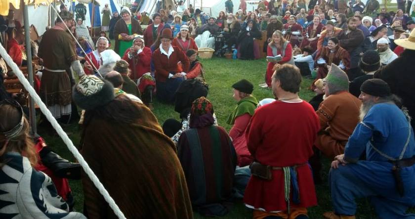 A photo of SCA royal court, many people in historical costumes.